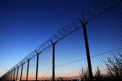 Barb wire fence at dusk - protection of Warsaw airport area (Poland).